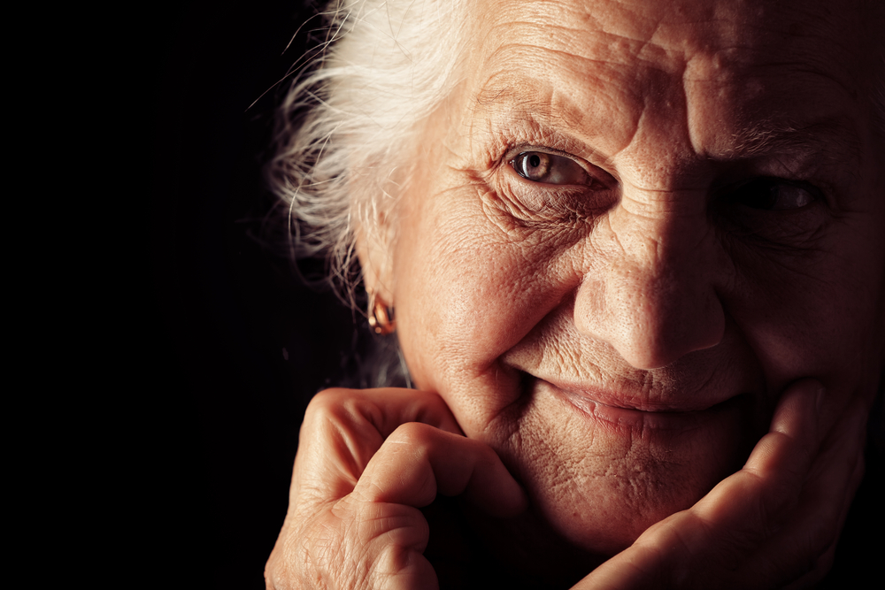 Portrait of a happy senior woman smiling at the camera. Over black background by Kiselev Andrey Valerevich