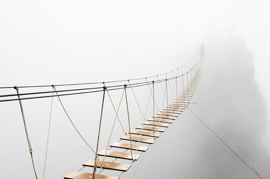 Fuzzy man walking on hanging bridge vanishing in fog. Focus on middle of bridge by Svetlana Lukienko